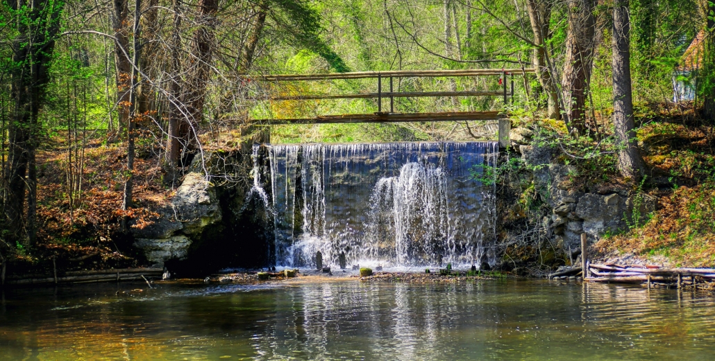 Servicios Urbanos, agua y ciudad - Cascada de agua, presa, represa, azud en monte con pasarela de madera y robles a la orilla Del Río