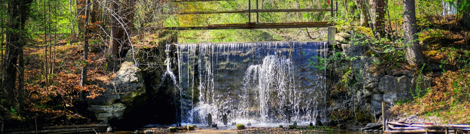 Servicios Urbanos, agua y ciudad - Cascada de agua, presa, represa, azud en monte con pasarela de madera y robles a la orilla Del Río